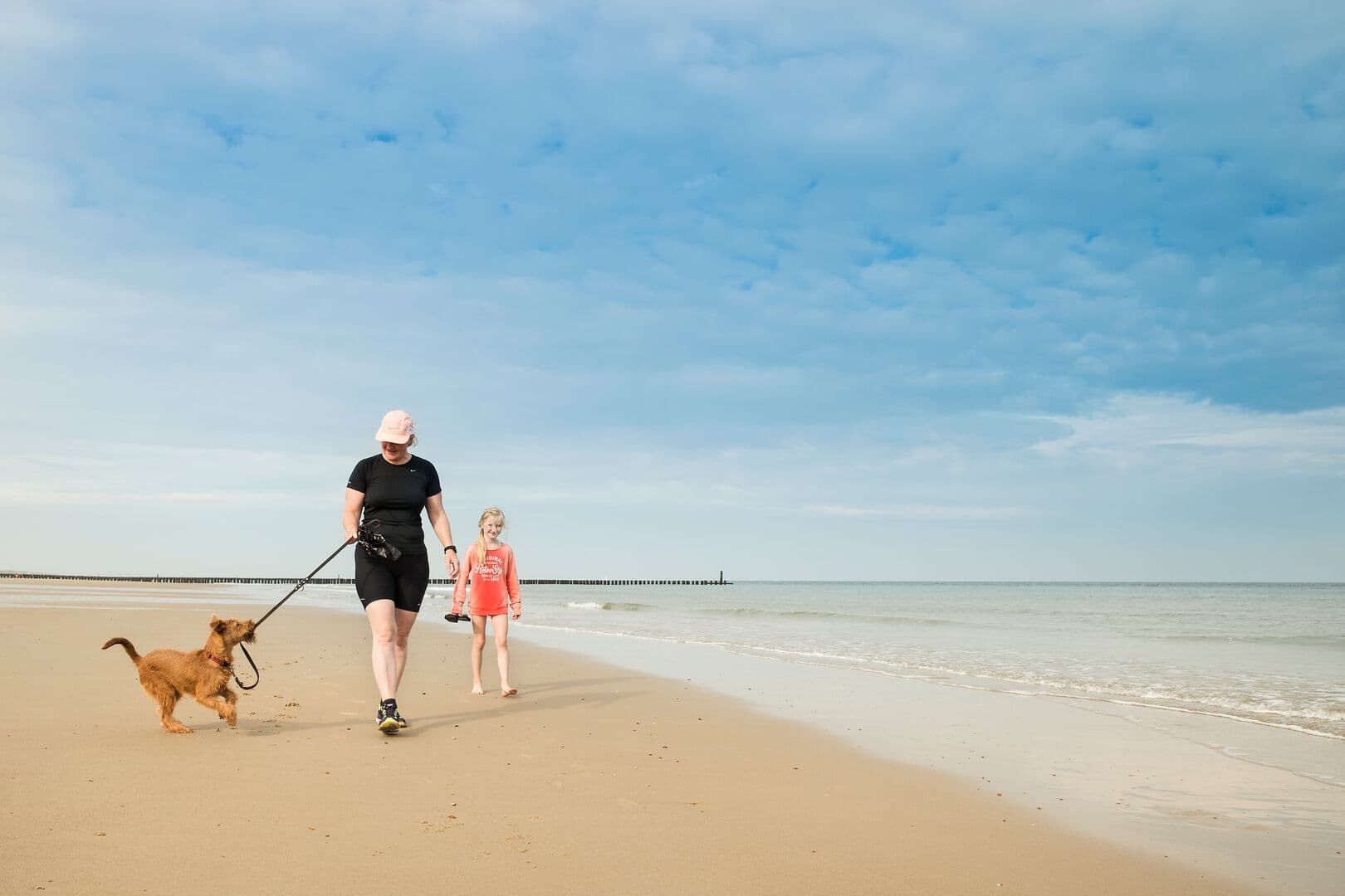Vrouw en kind laten hond uit op het strand Domburg